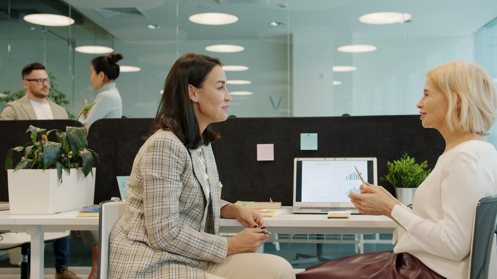 Deux femmes discutent ensemble à un bureau en consultant un ordinateur portable