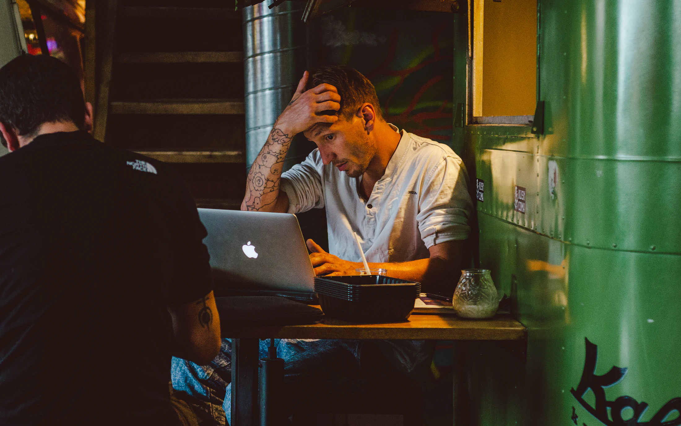 Un développeur stressé se frottant les yeux devant un ordinateur portable rempli de code
